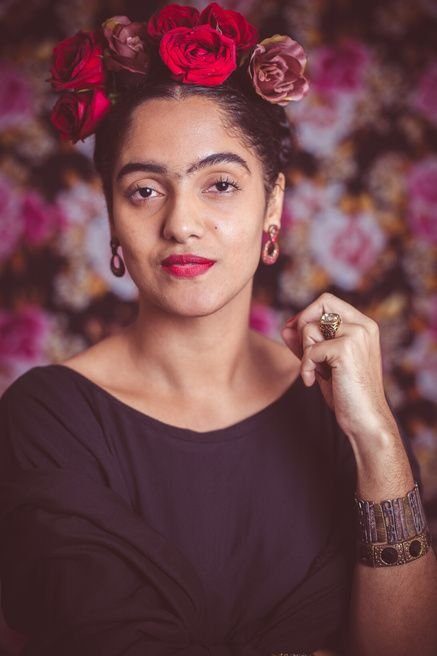 Retrato inspirado em Frida Kahlo, com flores vermelhas no cabelo